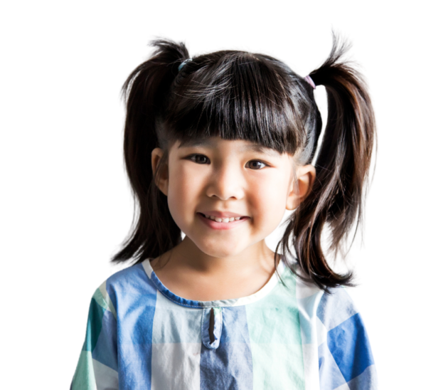 Smiling young girl with dark hair in pigtails, wearing a blue and white checkered shirt, standing against a plain white background.